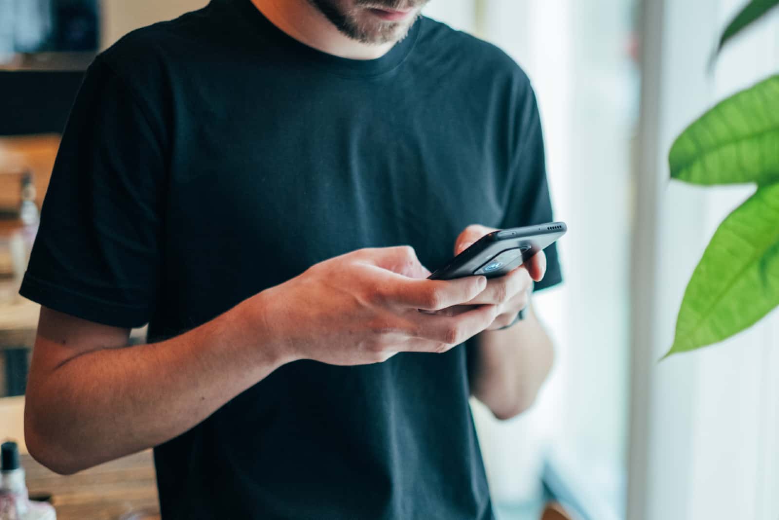 homme en t-shirt noir utilisant un smartphone