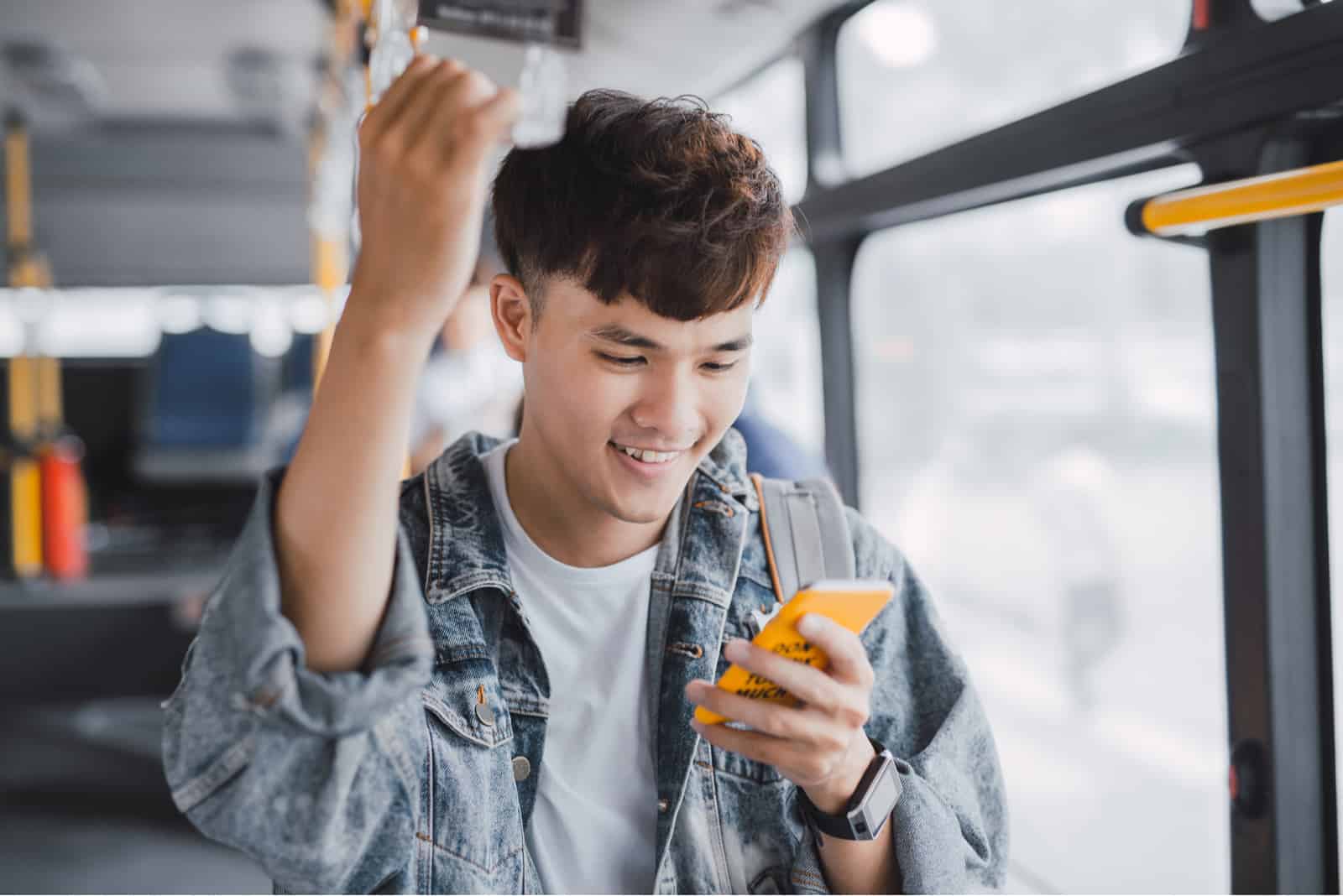 l'homme est debout dans le bus en utilisant le téléphone