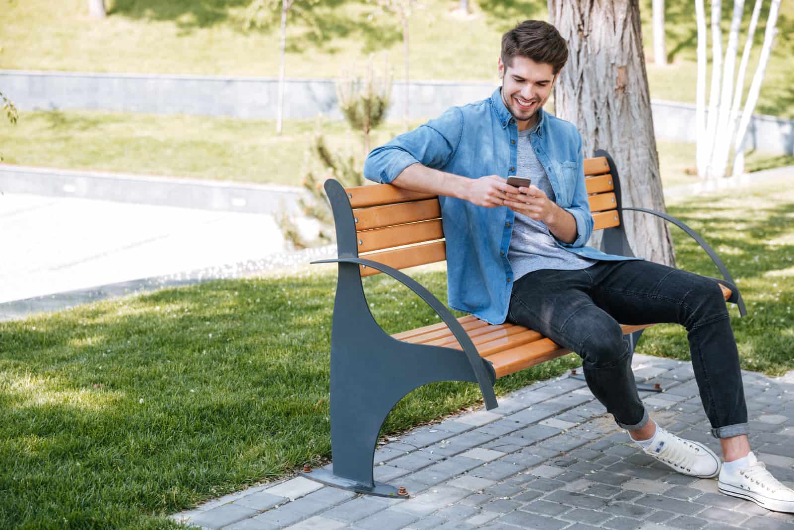 un homme est assis sur un banc de parc et les boutons du téléphone
