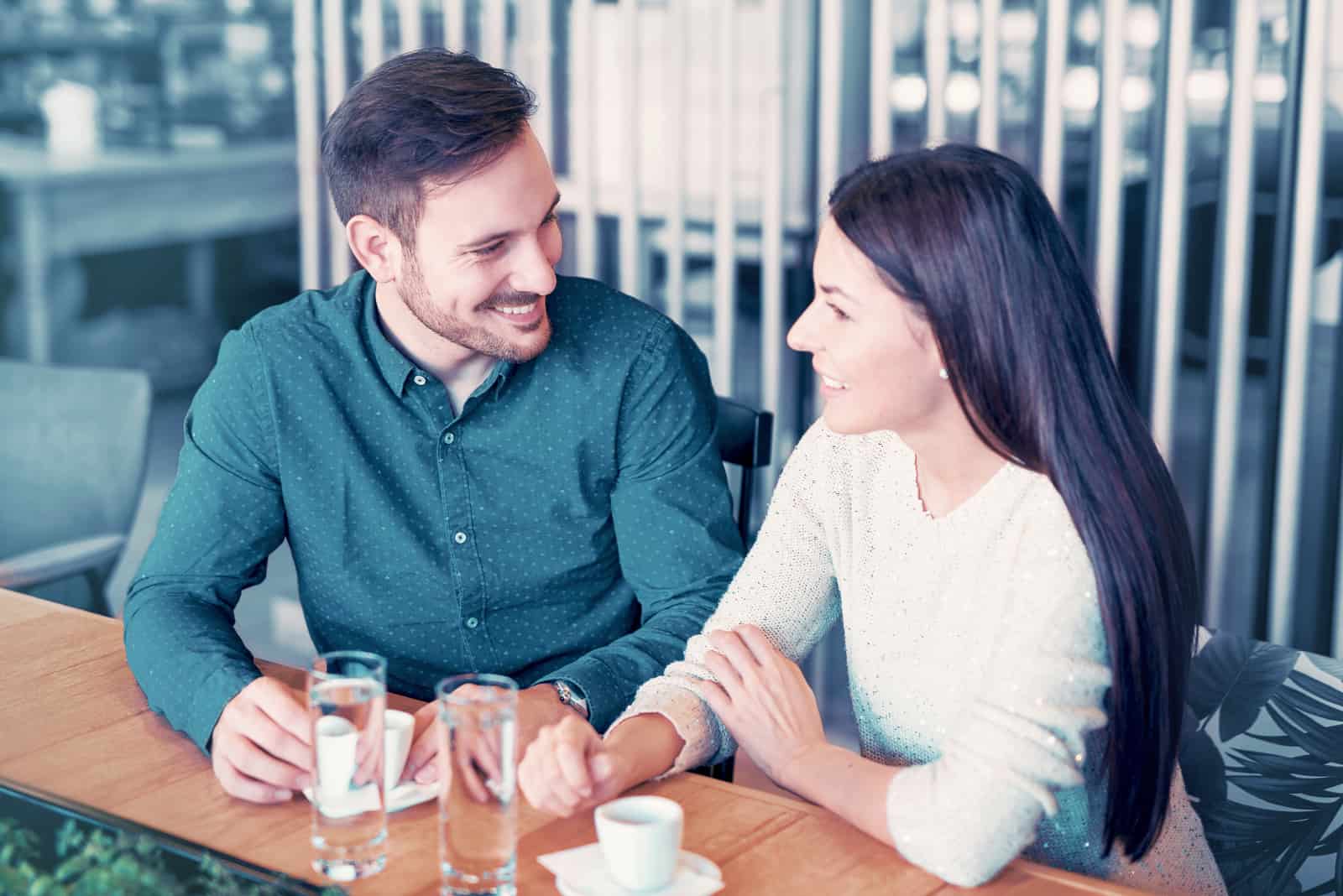 un homme et une femme rient en buvant du café