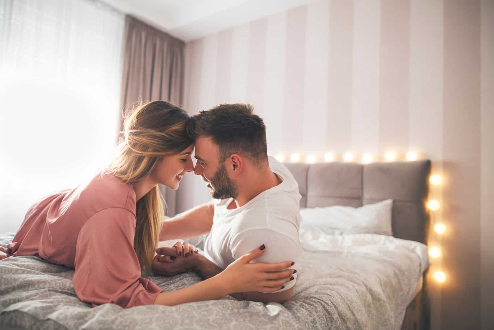 un homme et une femme s'allongent sur le lit et échangent de la tendresse