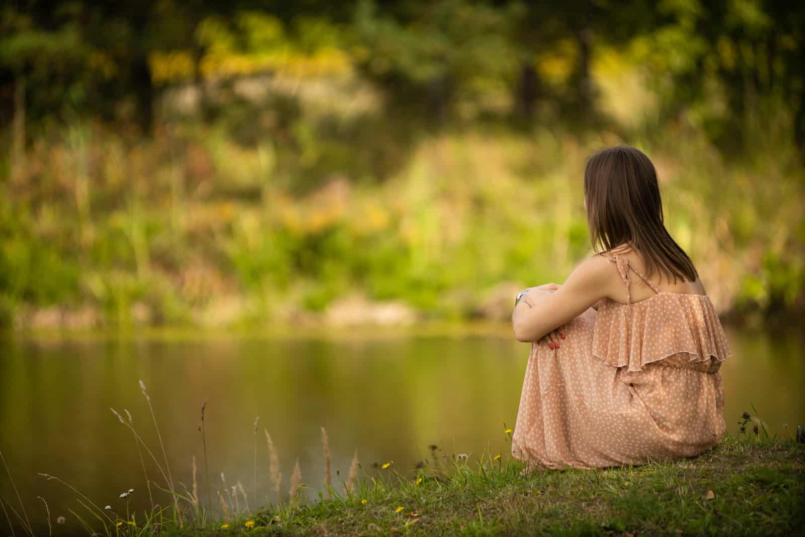 une femme imaginaire assise sur un pré au bord de la rivière