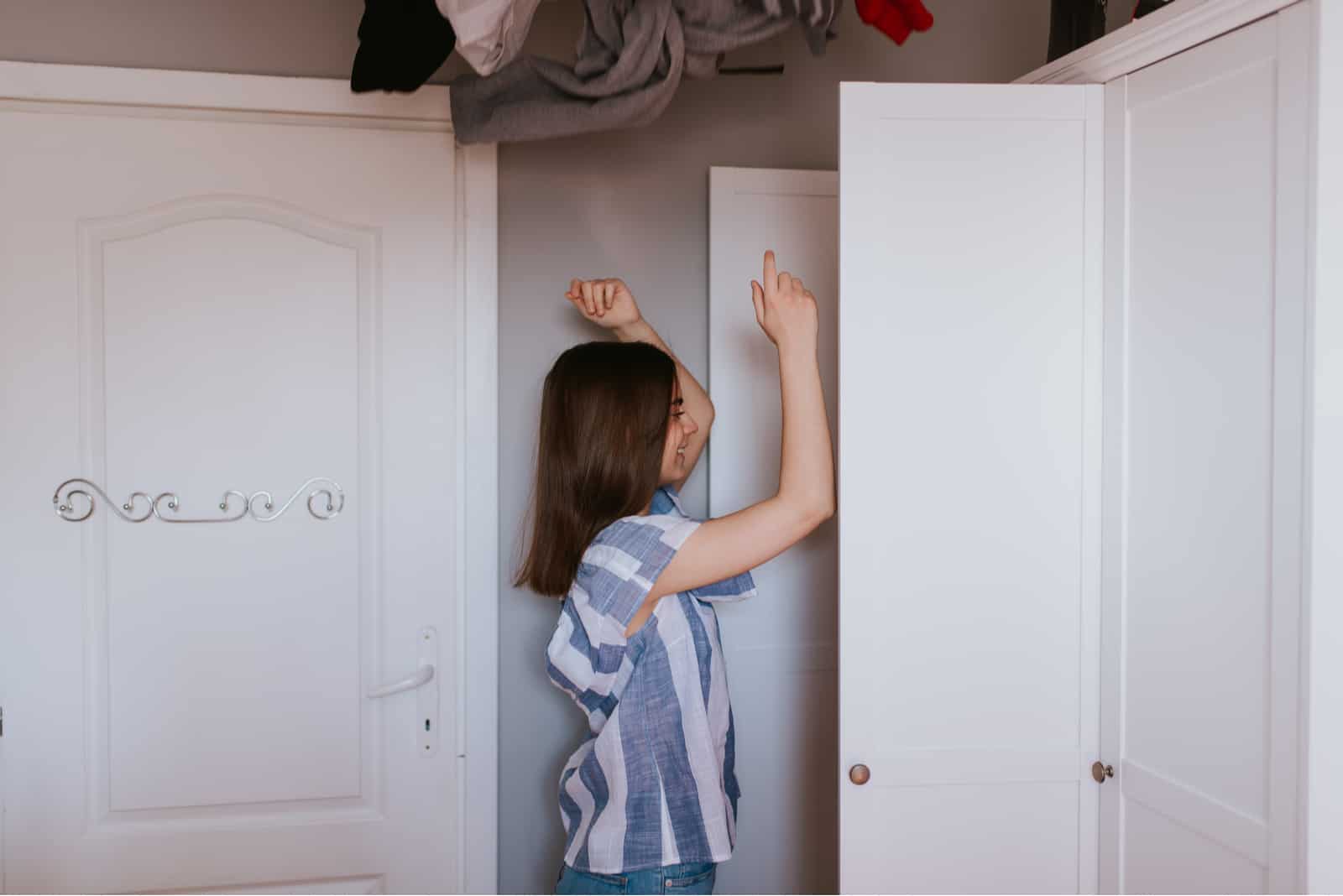 une fille souriante jette des vêtements hors du placard