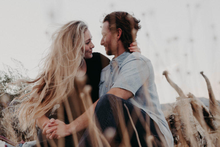 homme et femme se tenant la main assis dans un champ