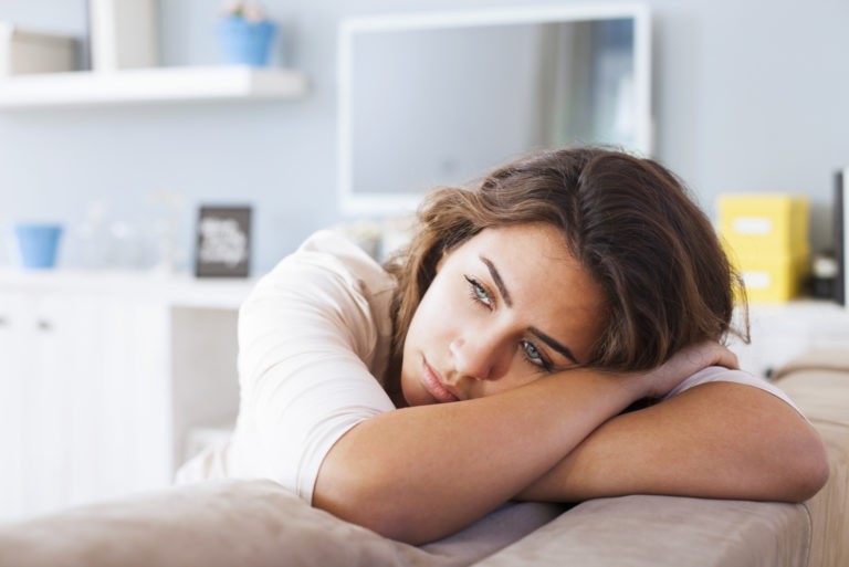 une femme triste appuyée contre le lit