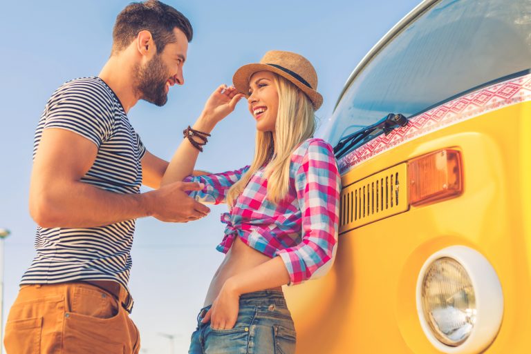un homme et une femme souriants se tiennent près du bus et parlent