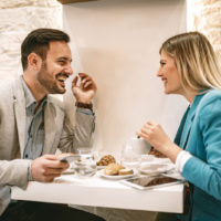 un homme et une femme s'assoient à une table et boivent du café