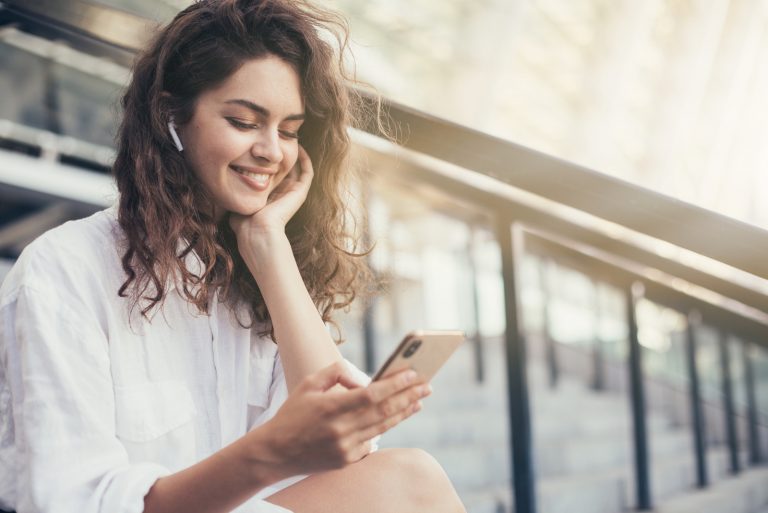 une femme souriante aux cheveux crépus est assise et les touches du téléphone