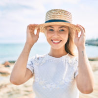 une femme souriante se tient avec un chapeau sur la tête