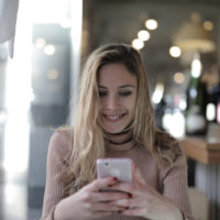 Femme heureuse utilisant un smartphone alors qu'elle est assise dans un café