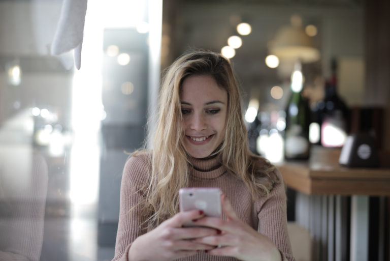 Femme heureuse utilisant un smartphone alors qu'elle est assise dans un café
