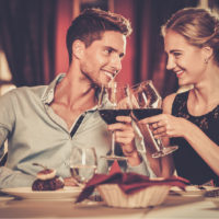 un homme et une femme trinquent avec un verre au dîner