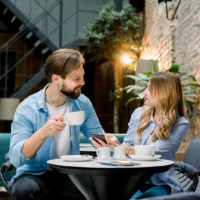 un homme et une femme sont assis dans un café et boivent du café