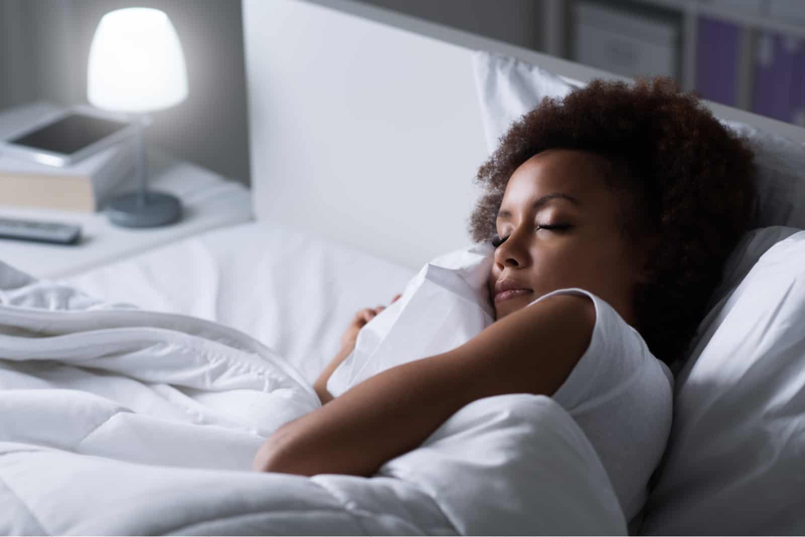 une femme aux cheveux crépus se couche et dort dans son lit