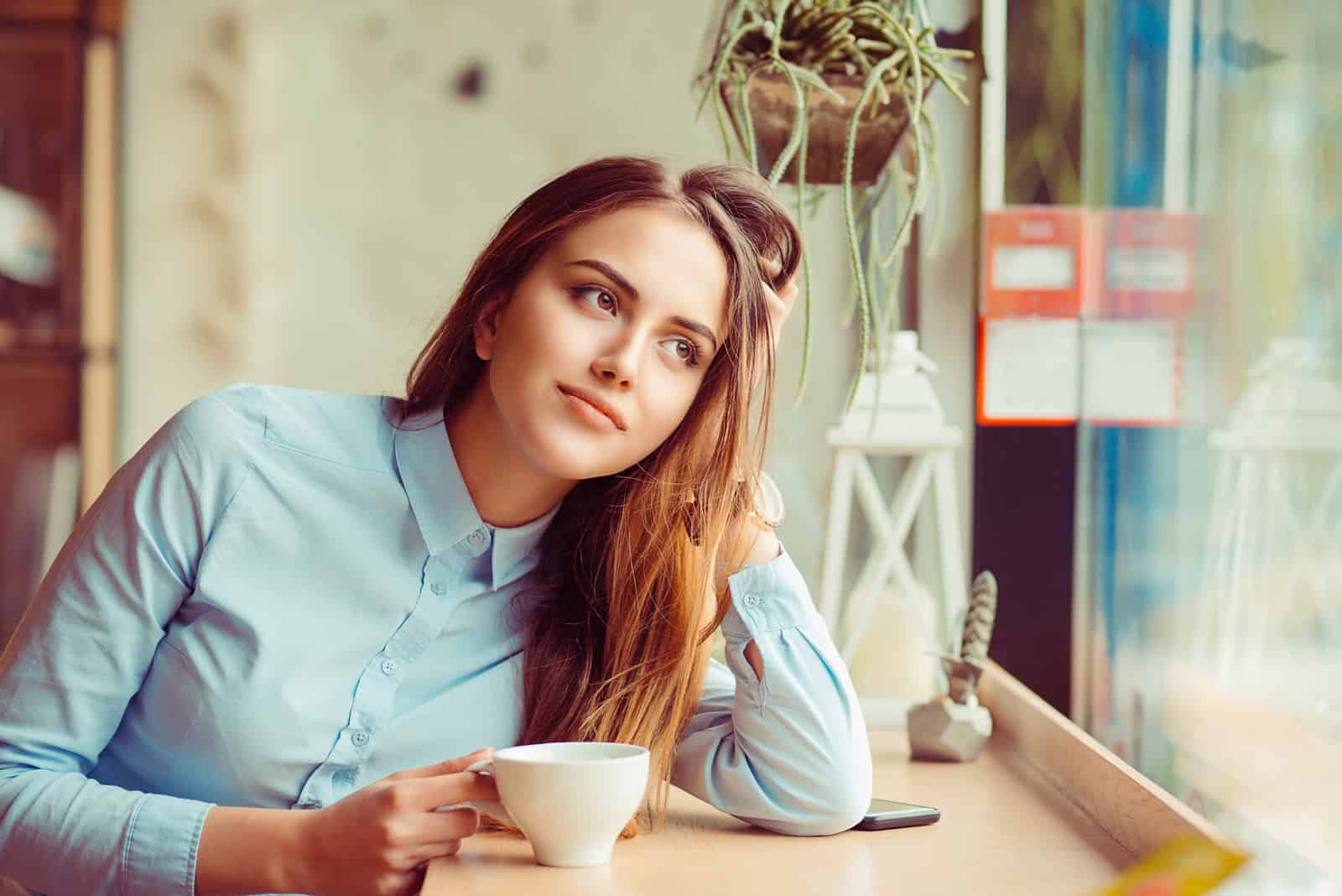 une femme imaginaire est assise et boit du café