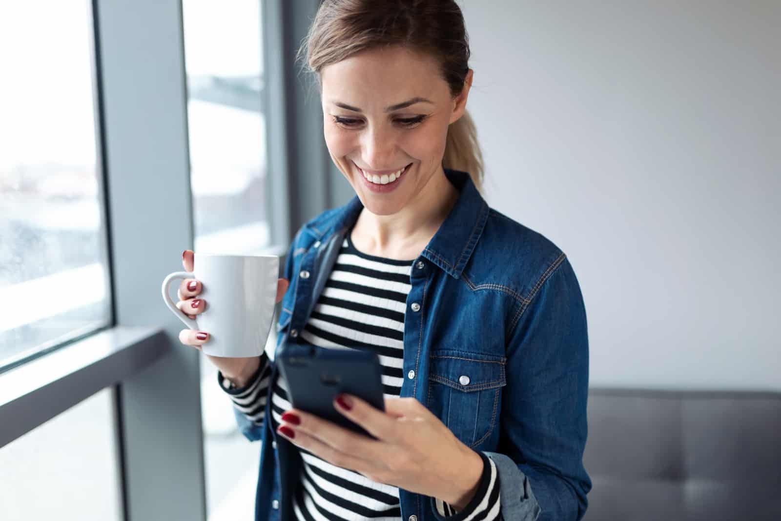 une femme souriante tenant une tasse de café et une clé au téléphone