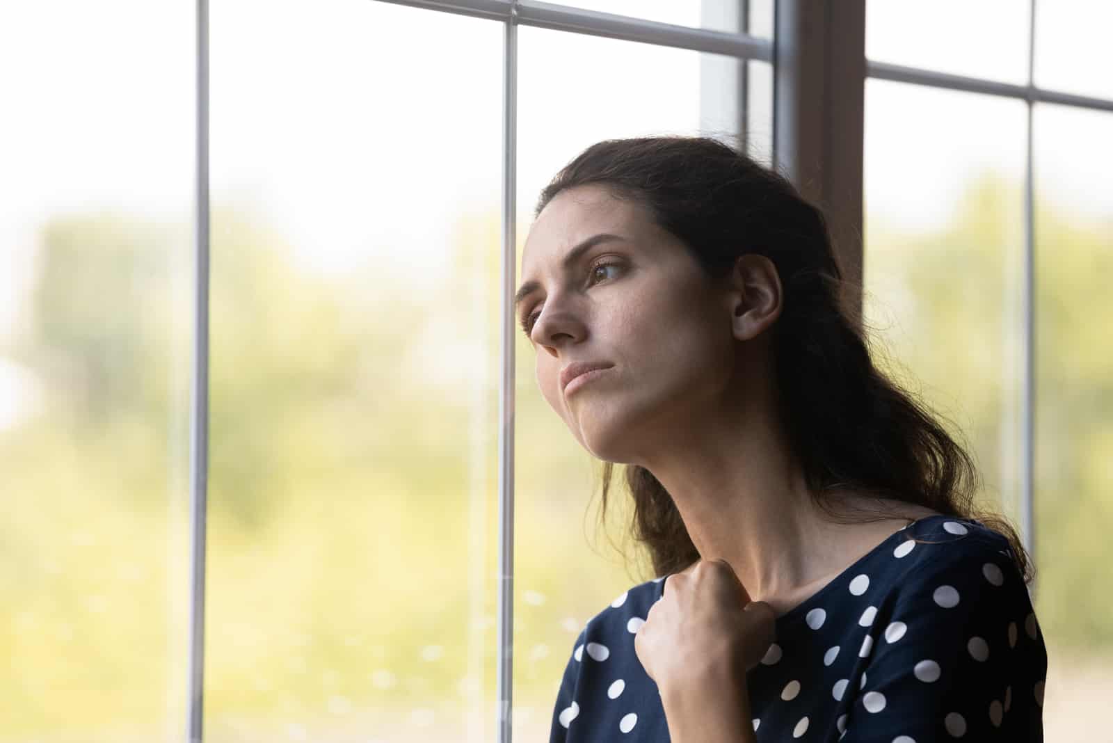 une femme triste est assise près de la fenêtre