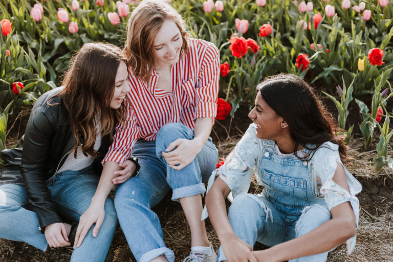 trois femmes souriantes assises près de tulipes
