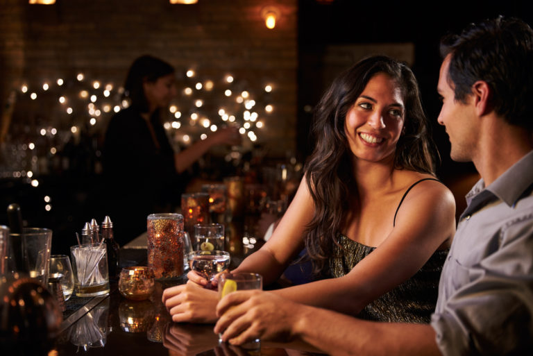 homme et femme parlant assis dans un bar