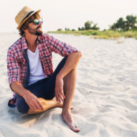 un homme souriant assis sur la plage