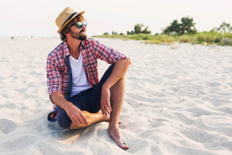 un homme souriant assis sur la plage