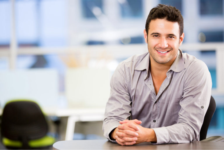 un homme souriant assis à une table