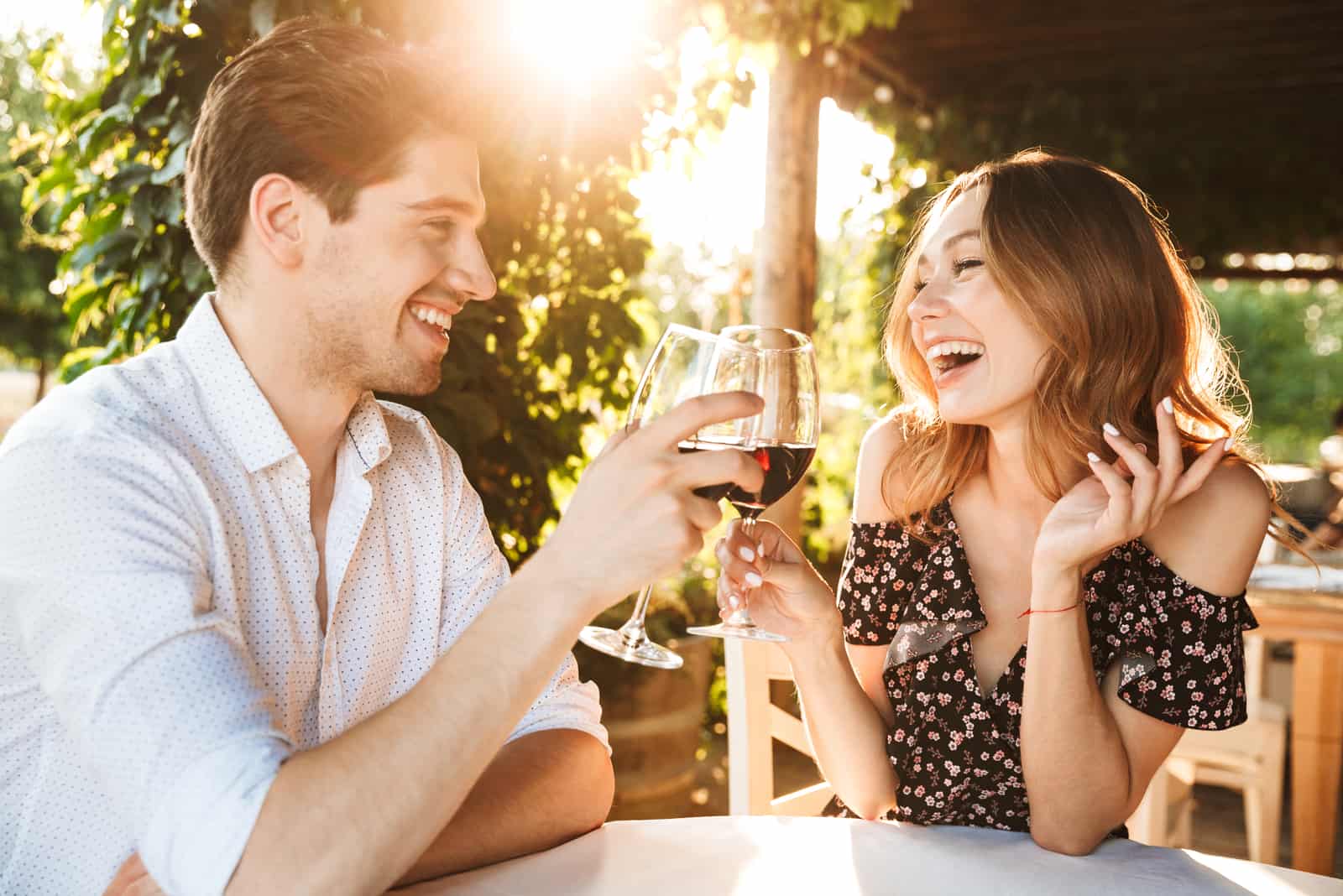 un homme souriant et une femme buvant du vin