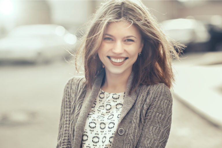 une belle femme aux longs cheveux bruns se tient dans la rue et rit