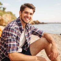 un homme souriant assis sur la plage