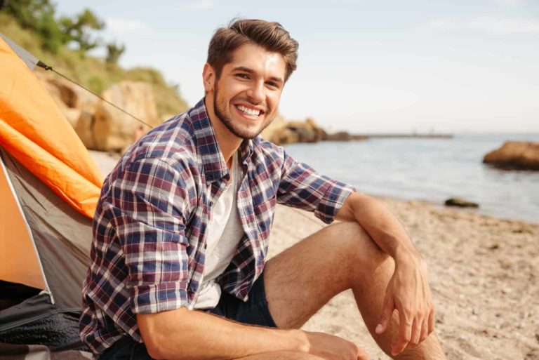 un homme souriant assis sur la plage