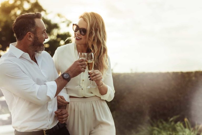 un homme et une femme se tiennent debout et trinquent avec du vin