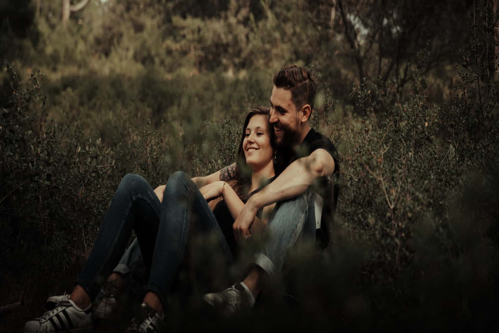 homme et femme souriant assis sur l'herbe