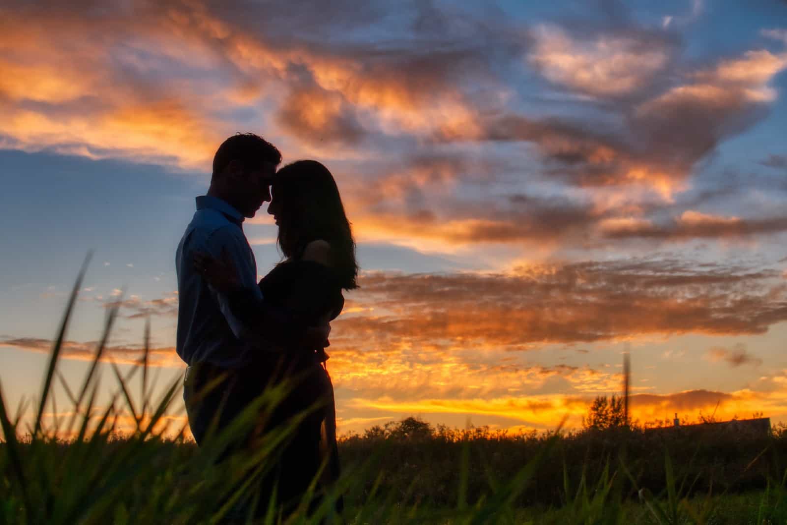 homme et femme s'embrassant en se tenant dans un champ