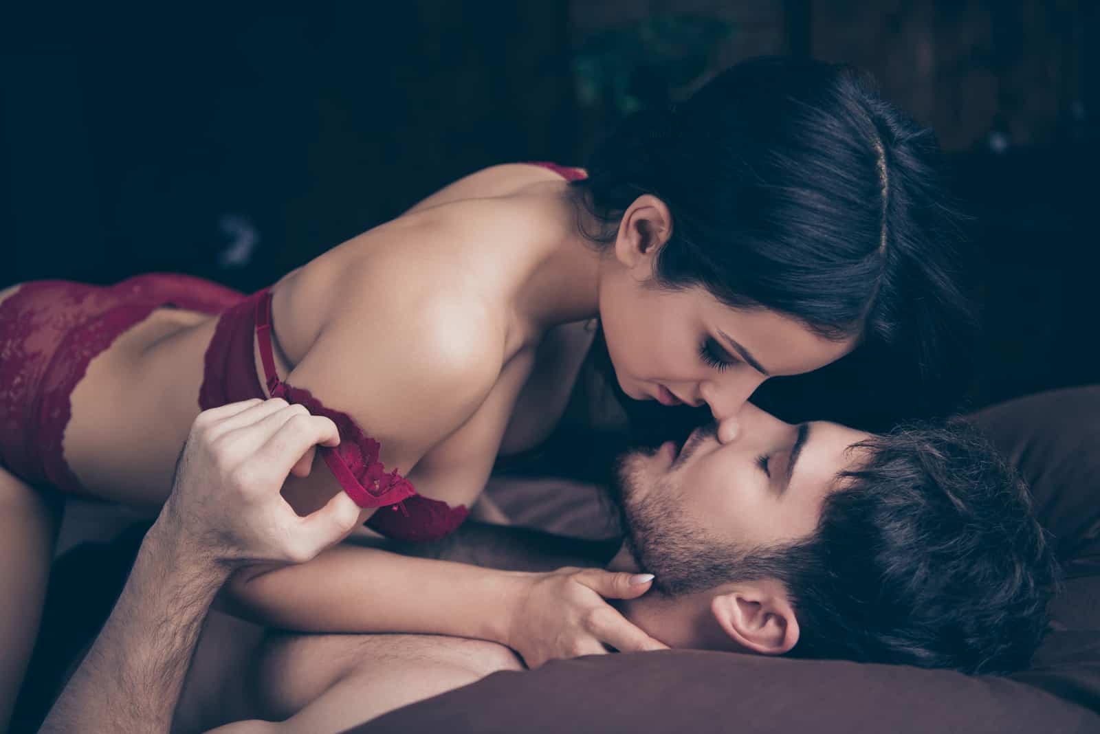 homme et femme sur le point de s'embrasser en étant allongés sur le lit