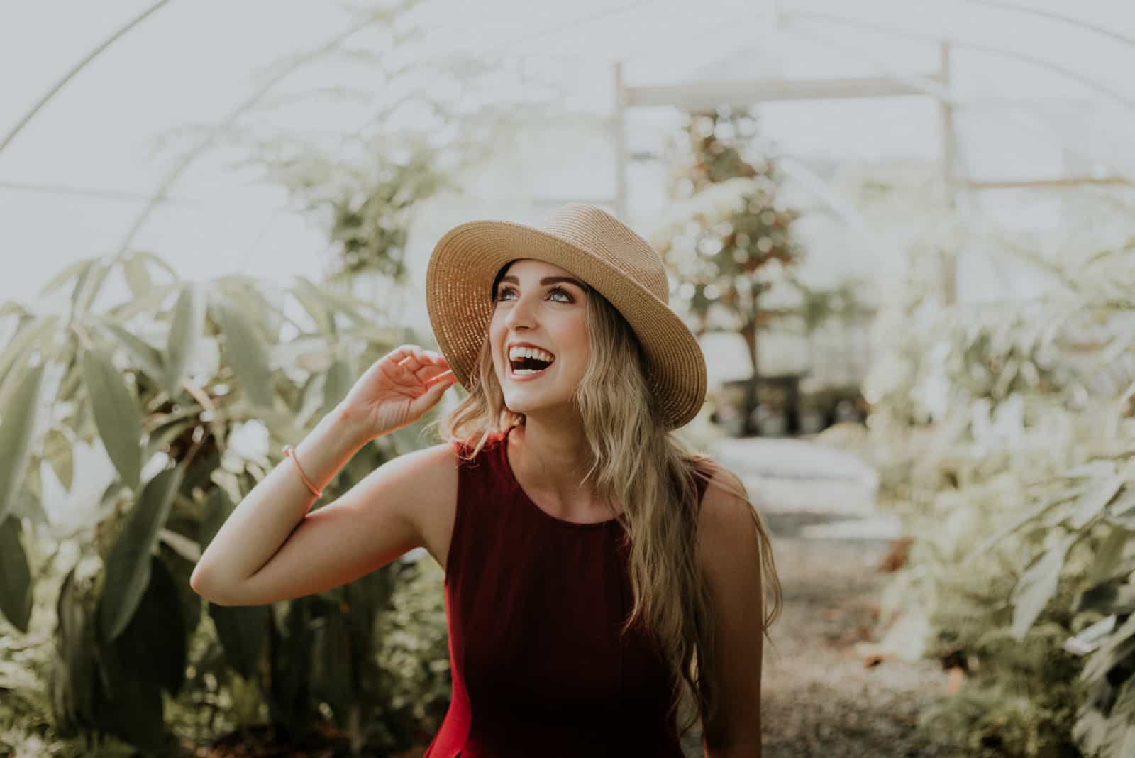 femme heureuse avec un chapeau debout près de plantes