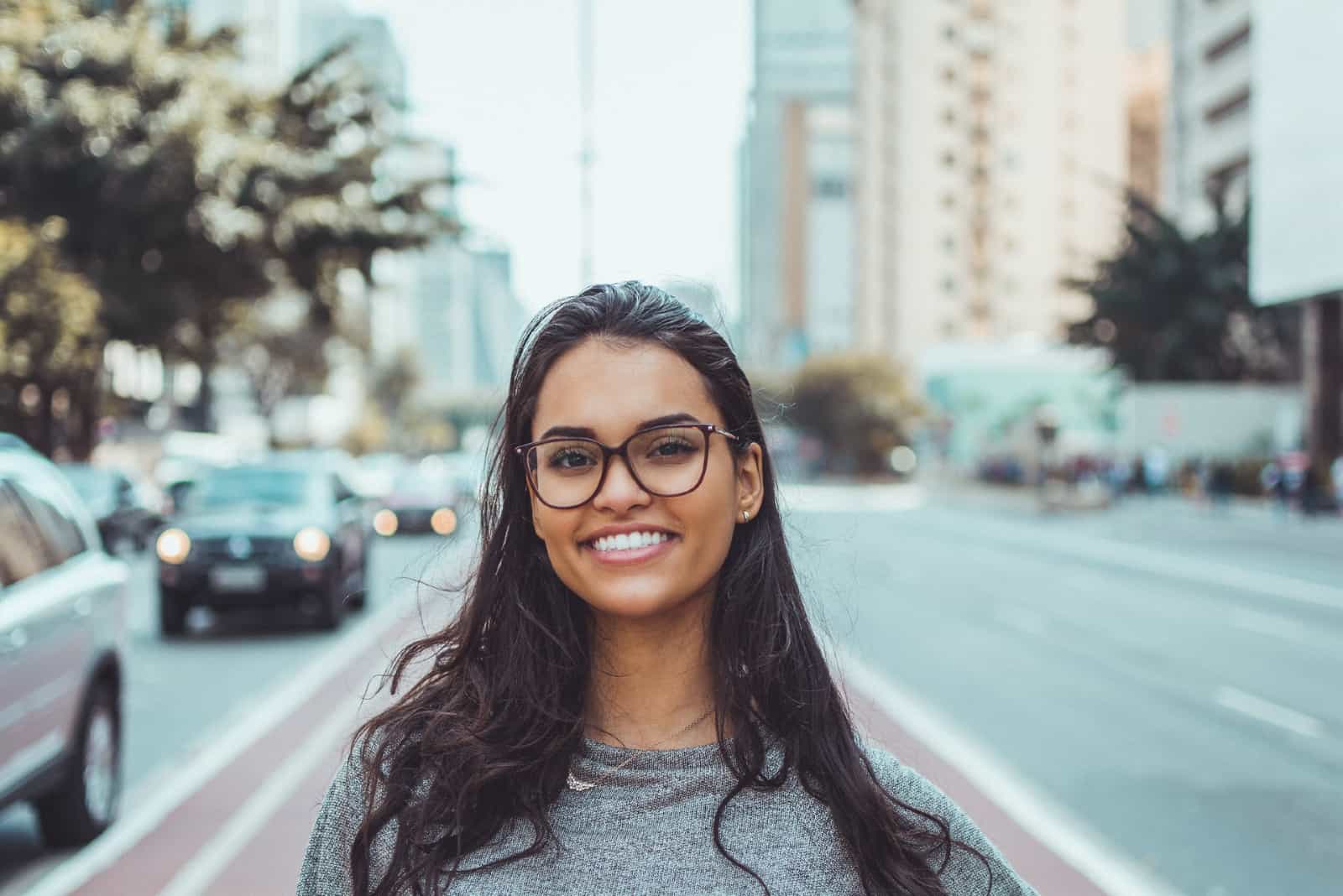 Femme heureuse avec des lunettes debout près d'une route