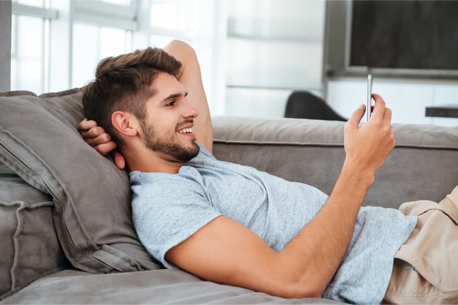 homme allongé sur un canapé en regardant son smartphone