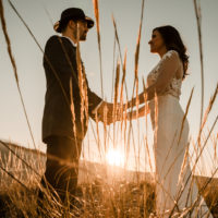 un homme et une femme se tenant la main dans un champ de blé