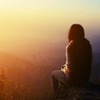 une femme triste est assise sur un rocher et regarde devant elle