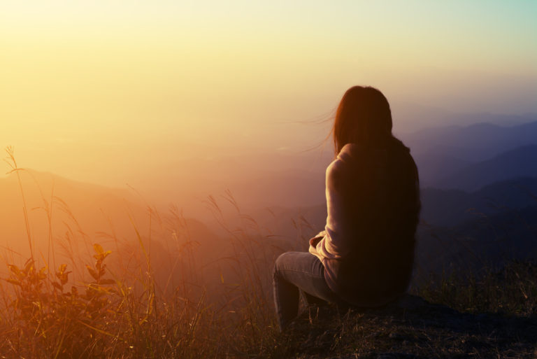 une femme triste est assise sur un rocher et regarde devant elle