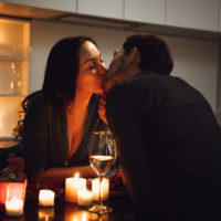 un homme et une femme sont assis à une table et s'embrassent