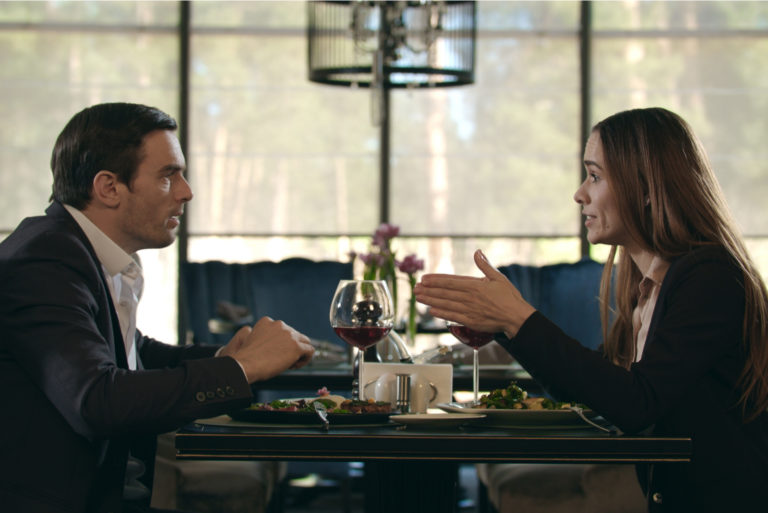 un homme et une femme sont assis à une table et se disputent