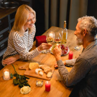 un homme et une femme souriants trinquent avec du vin pendant le dîner