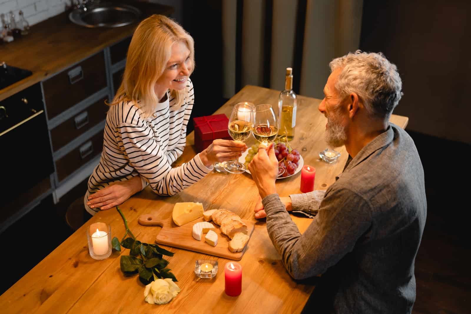 un homme et une femme souriants trinquent avec du vin pendant le dîner