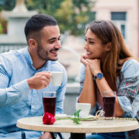un beau jeune couple assis à l'extérieur et parlant autour d'un café