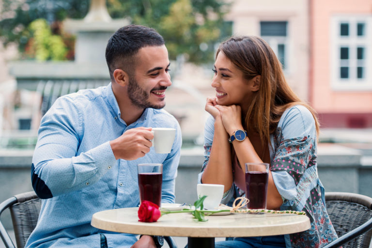 un beau jeune couple assis à l'extérieur et parlant autour d'un café