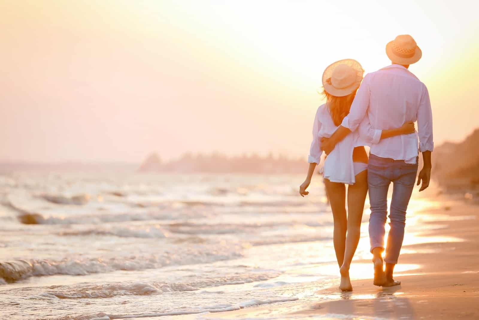 un homme et une femme marchent le long de la plage en s'embrassant