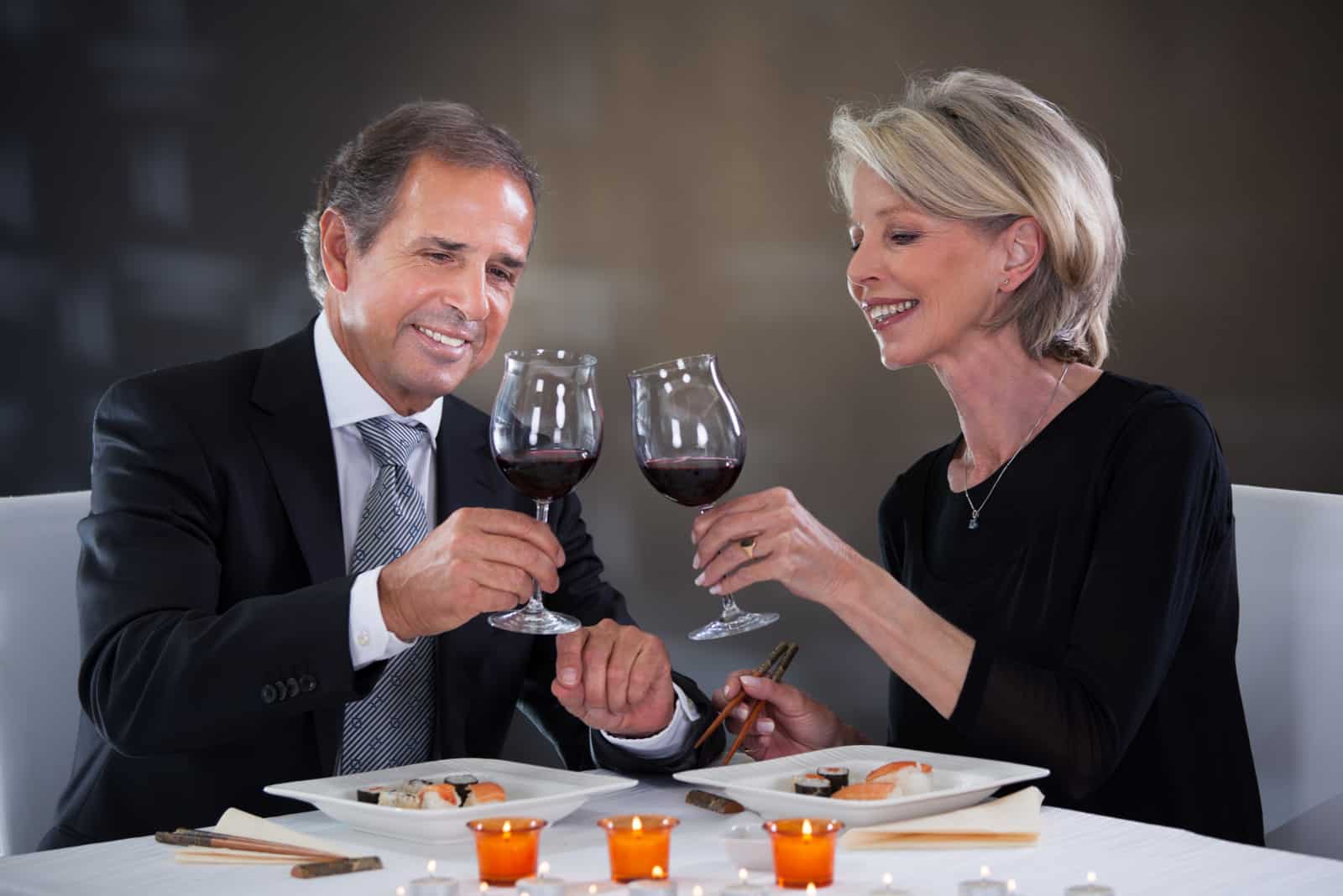 un homme et une femme s'assoient à une table et trinquent avec du vin