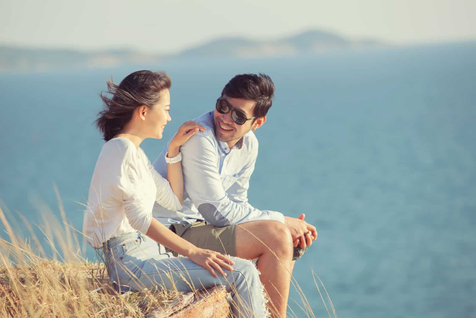 un homme et une femme sont assis sur un rocher et parlent