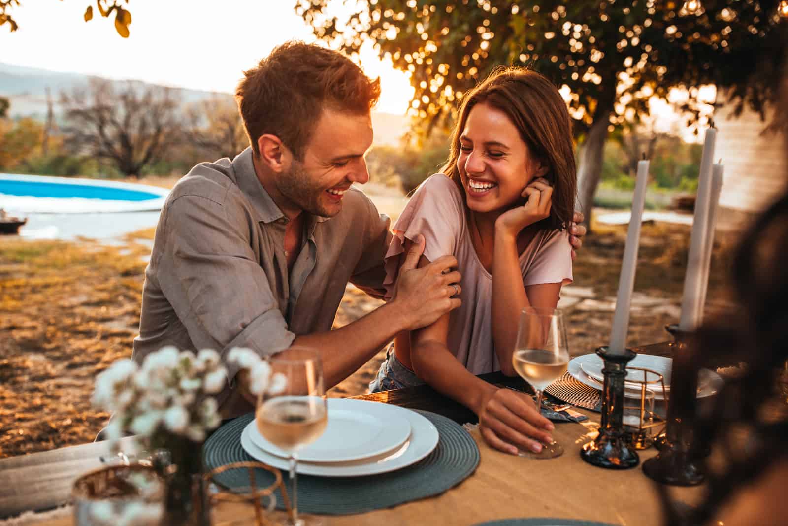 un homme et une femme souriants assis à une table à l'extérieur